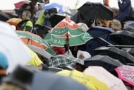 Spectators open their umbrella as rain falls over the Suzanne Lenglen court in Paris on May 30, 2013